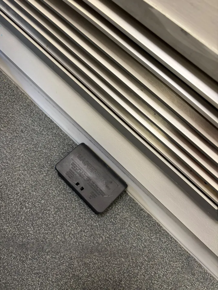 Boîtier de dératisation fermé le long d’une plinthe sous une grille